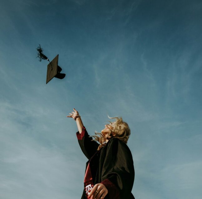 Three graduates in caps and gowns holding diplomas