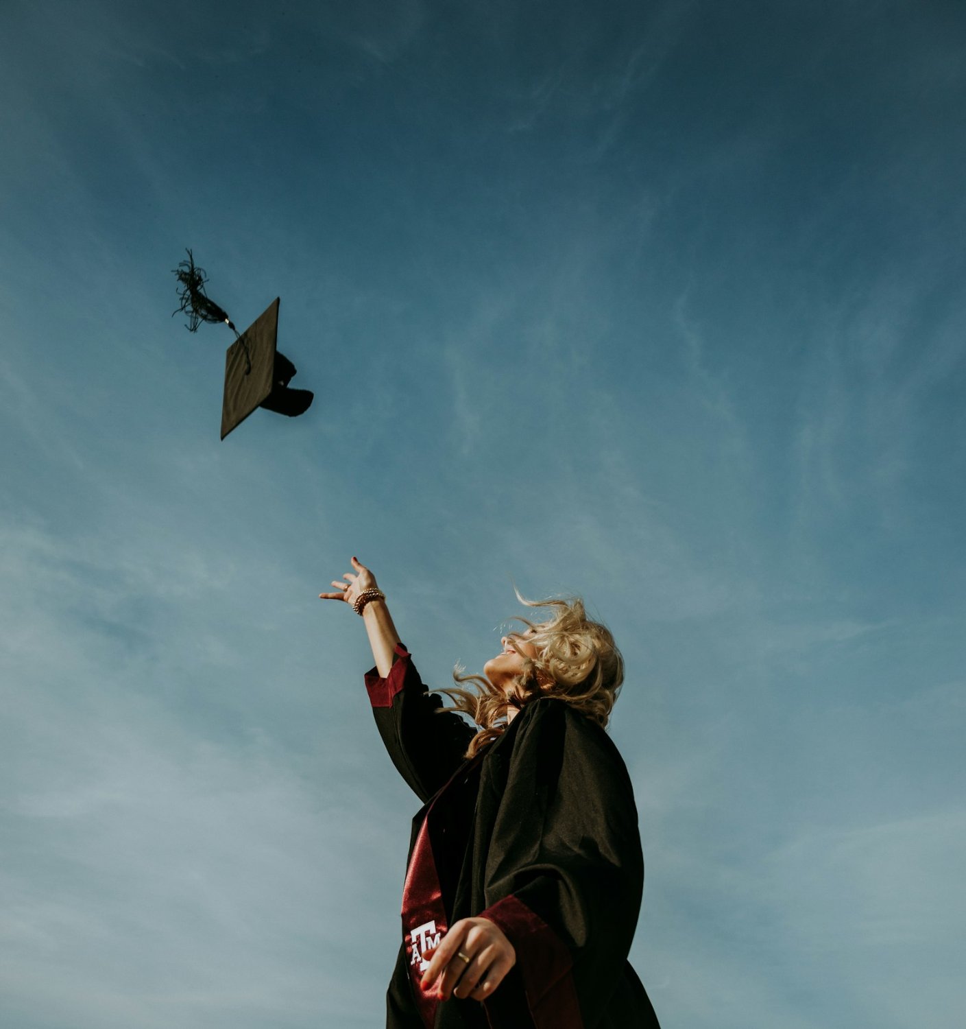 Three graduates in caps and gowns holding diplomas